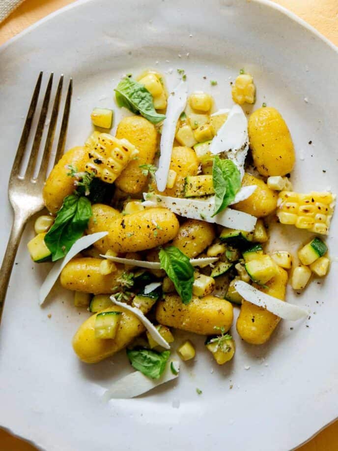 Summer corn gnocchi with corn and zucchini and a fork on the side.