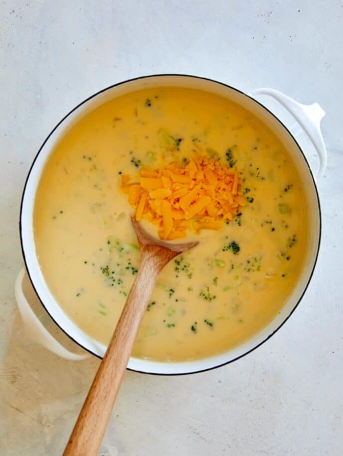 Adding in cheddar cheese to make broccoli cheddar soup.