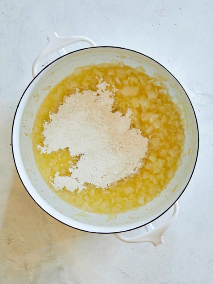 Flour added into a stock pot with melted butter and onions.