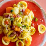 Butternut squash Orecchiette pasta on a red plate.