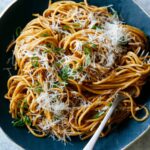 Garlic noodles in a bowl with parmesan on top with a fork twisted in some noodles.