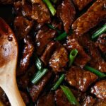 Mongolian beef in a skillet with green onions.