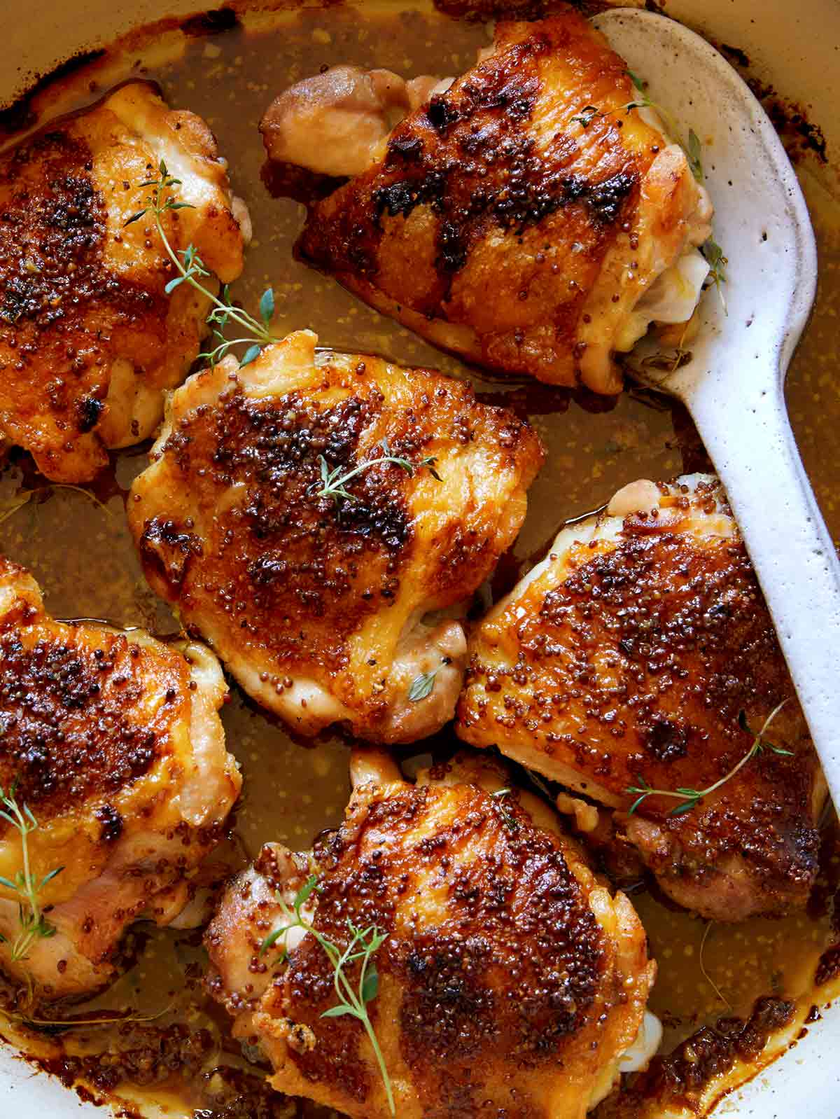 A close up on oven baked chicken thighs with a serving spoon under a chicken thigh.