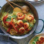 Singapore noodles recipe in a skillet being served onto two other plates.