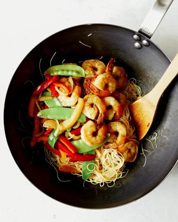 Singapore noodles recipe in a wok with shrimp and veggies.
