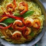 Singapore noodles in a big serving dish with plates on the side.
