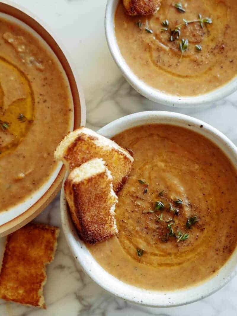 Three bowls of leftover vegetable soup and some toasted bread. 