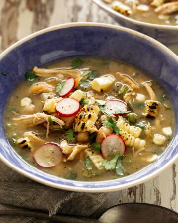 White bean chili in a blue bowl with toppings.