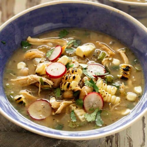 White bean chili in a blue bowl with toppings.