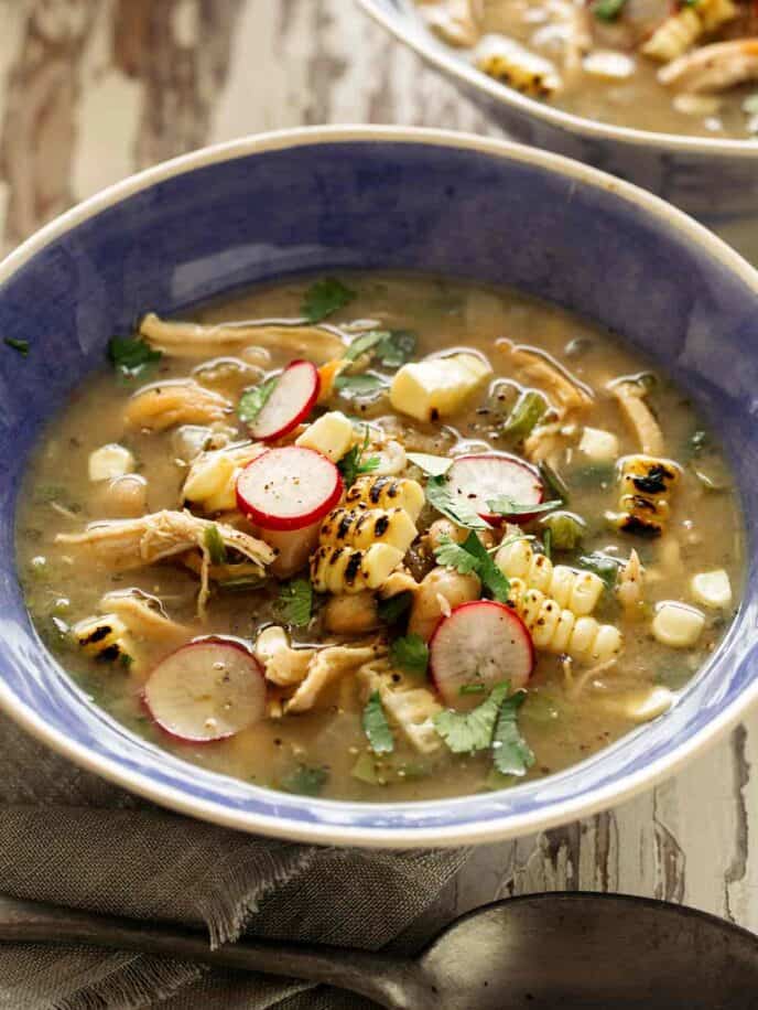 White bean chili in a blue bowl with toppings. 