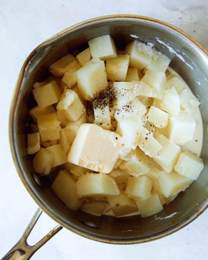 A pot of cooked potatoes with butter and cream, and salt and pepper. 