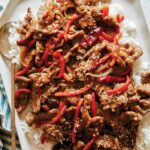 Szechuan beef recipe on a platter with a napkin underneath.