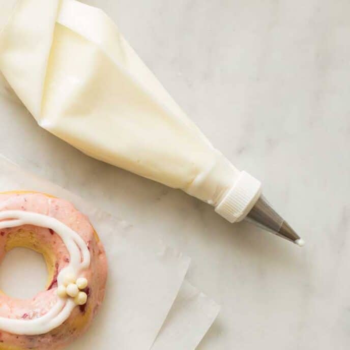 Piping bag with vanilla icing on a marble surface. 