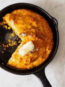 Pumpkin Cornbread in a skillet with butter on top.