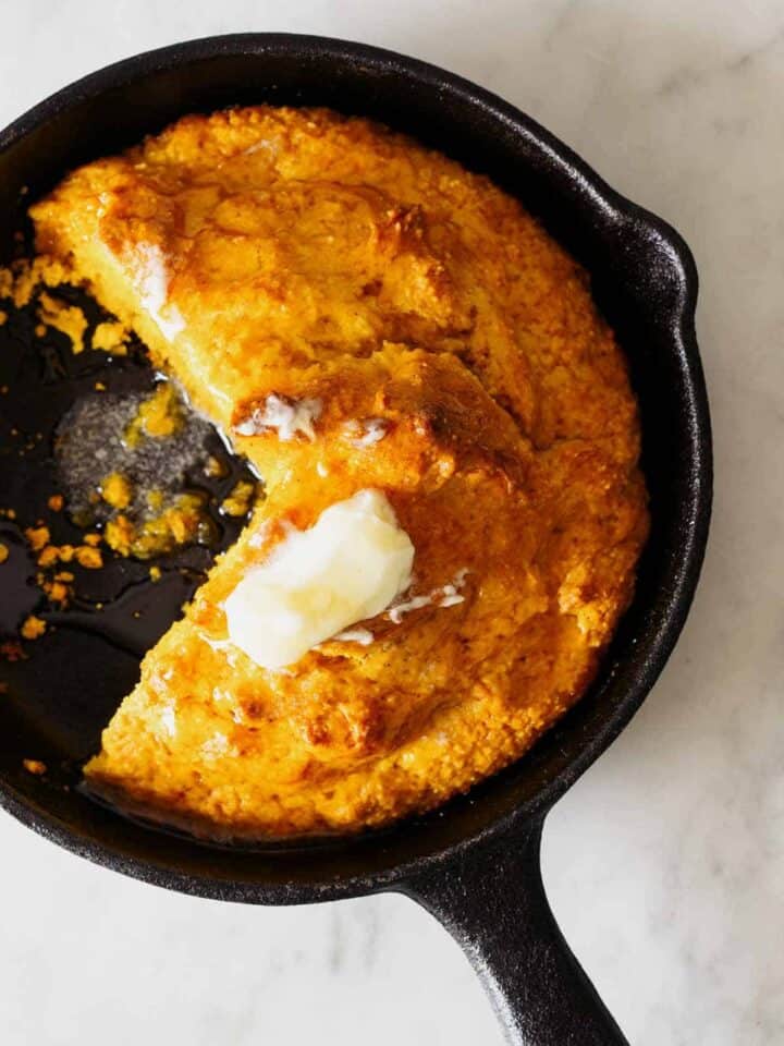 Pumpkin Cornbread in a skillet with butter on top.