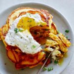 A plate of cheesy pumpkin pancakes with a fork digging into them.