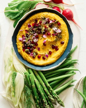 Roasted pumpkin hummus in a bowl with vegetables on the side, part of our Thanksgiving appetizers collection.