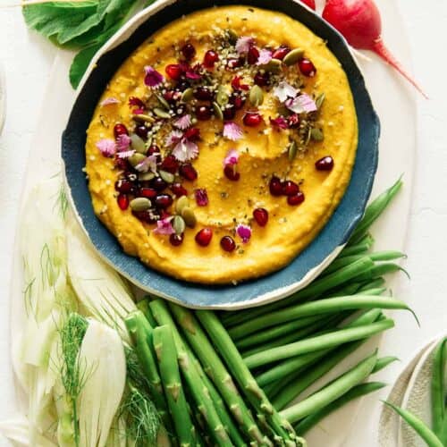 Roasted pumpkin hummus in a bowl with vegetables on the side, part of our Thanksgiving appetizers collection.