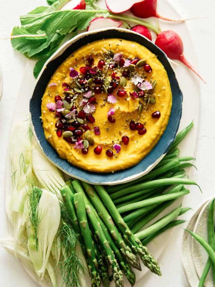 Roasted pumpkin hummus in a bowl with vegetables on the side, part of our Thanksgiving appetizers collection. 