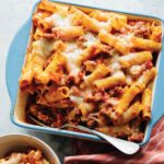 Baked Ziti in a casserole dish with a spoon in it.