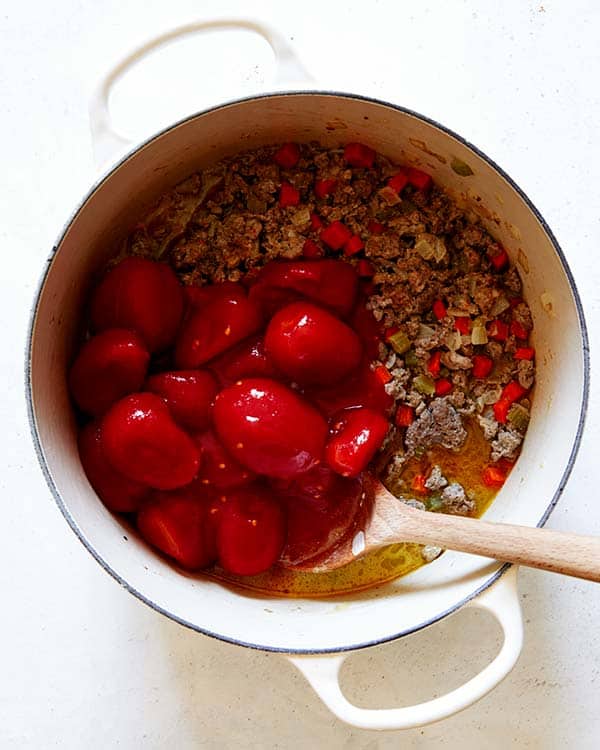 Tomatoes added into a stock pot to make a bolognese sauce.