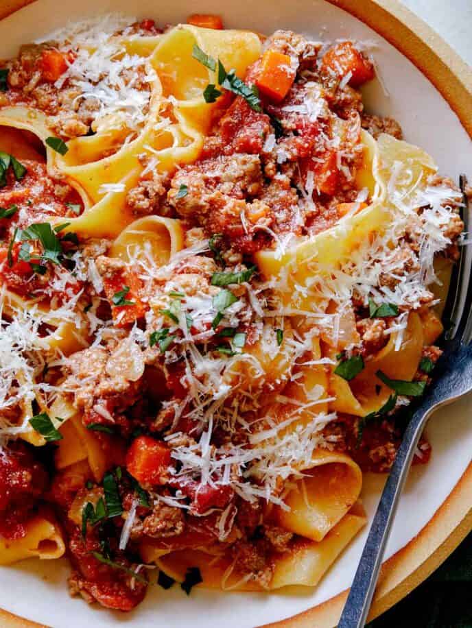 A bowl of bolognese sauce close up on a bowl with a fork.