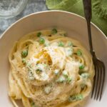 Fettuccine alfredo in a bowl with peas.