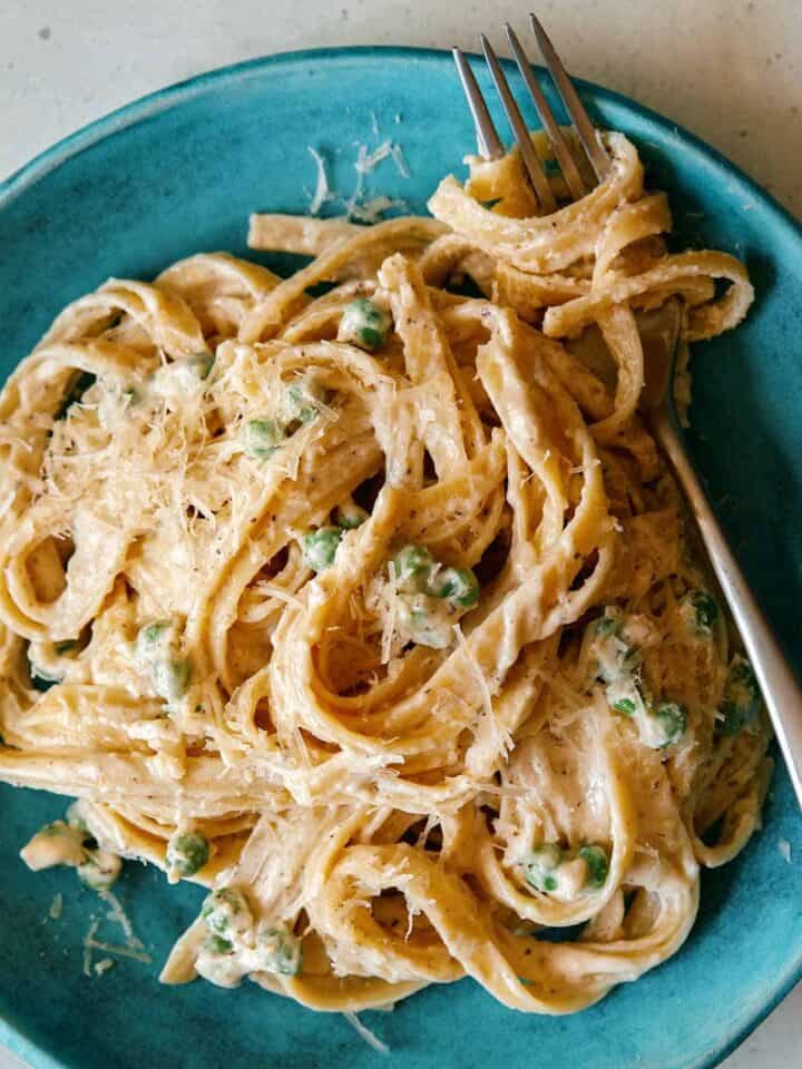 Browned Butter Fettuccine alfredo with peas on a plate with a fork in the pasta.