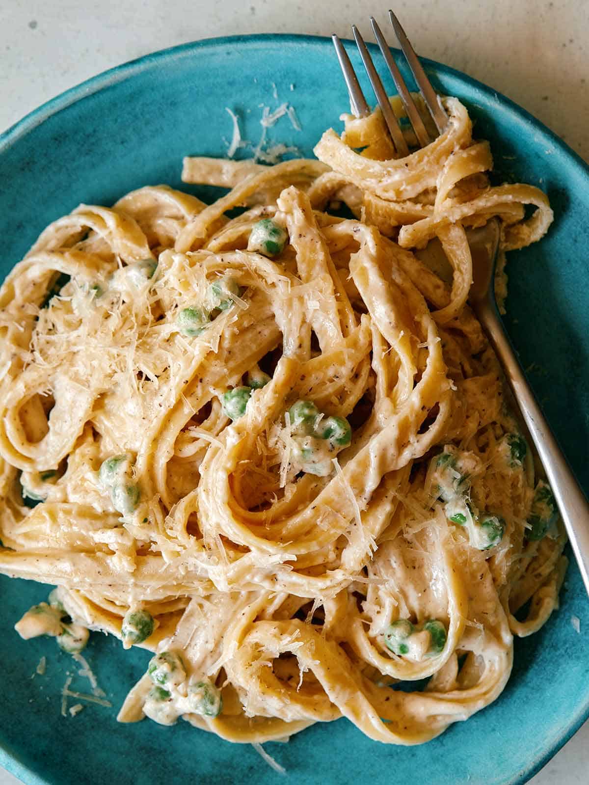 Browned Butter Fettuccine alfredo with peas on a plate with a fork in the pasta.