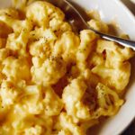 A bowl with cauliflower mac and cheese and a napkin under it.