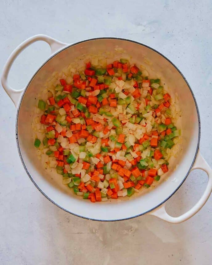 Onions, celery, and carrots in a stock pot sautéing with butter.