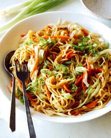 Chow Mein Noodles in a big bowl with a fork and spoon in it to serve.