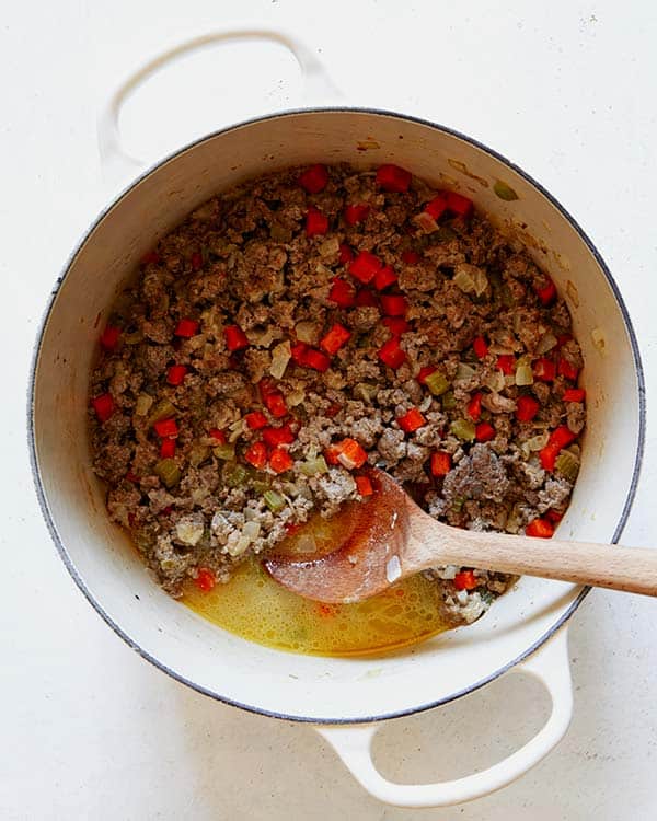 Cooking down meat to make a bolognese sauce in a pot.