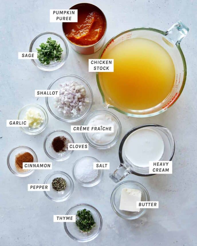 Ingredients to make Creamy Pumpkin Soup all laid out and labeled on a kitchen counter.