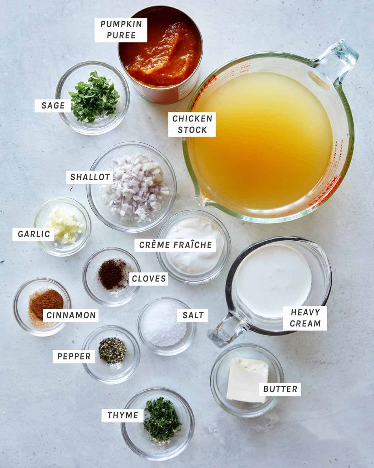 Ingredients to make Creamy Pumpkin Soup all laid out and labeled on a kitchen counter. 