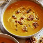 Two bowls of creamy pumpkin soup.