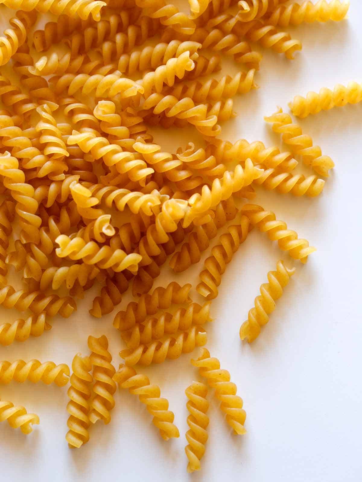 Raw and dried fusilli pasta spread out on a surface.