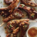 Garlic Butter Lamb Chops on a platter with a stack of plated next to it.