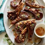 Garlic Butter Lamb Chops on a platter with a stack of plated next to it.