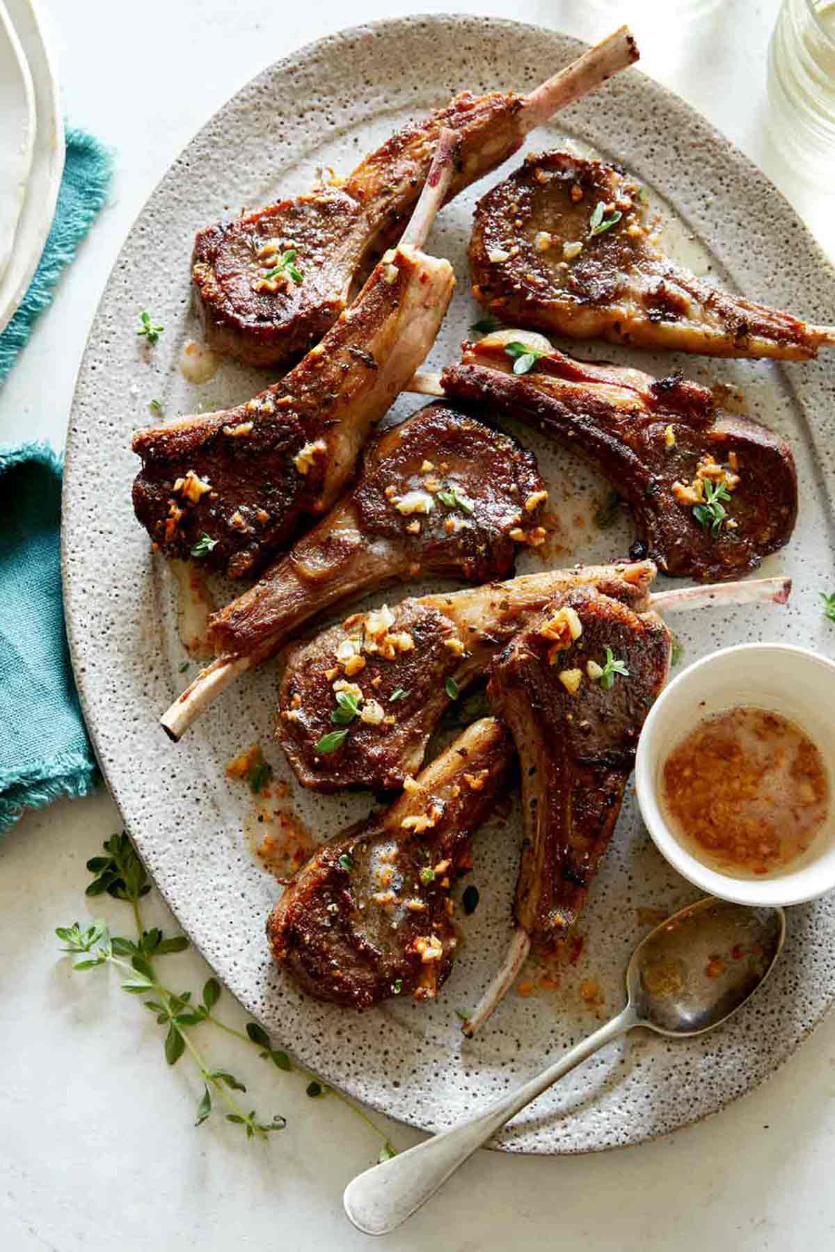 Garlic Butter Lamb Chops on a platter with a stack of plated next to it.