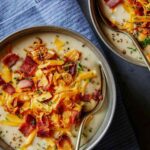 A bowl of loaded baked potato with a spoon in it.