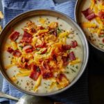 Bowls of loaded baked potato soup with spoons.