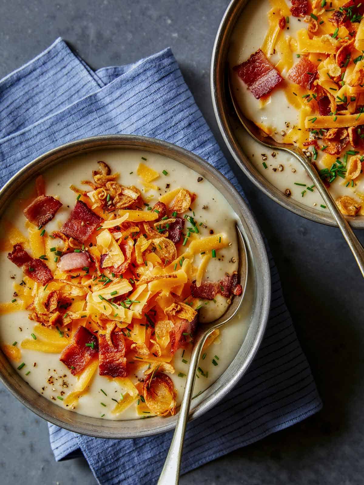 Bowls of loaded baked potato soup with spoons.