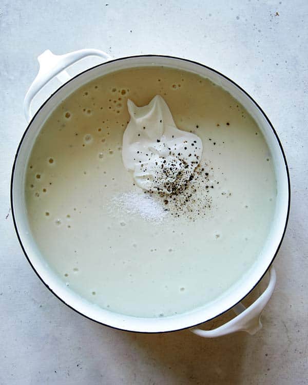 Loaded baked potato soup in a stock pot with sour cream added.