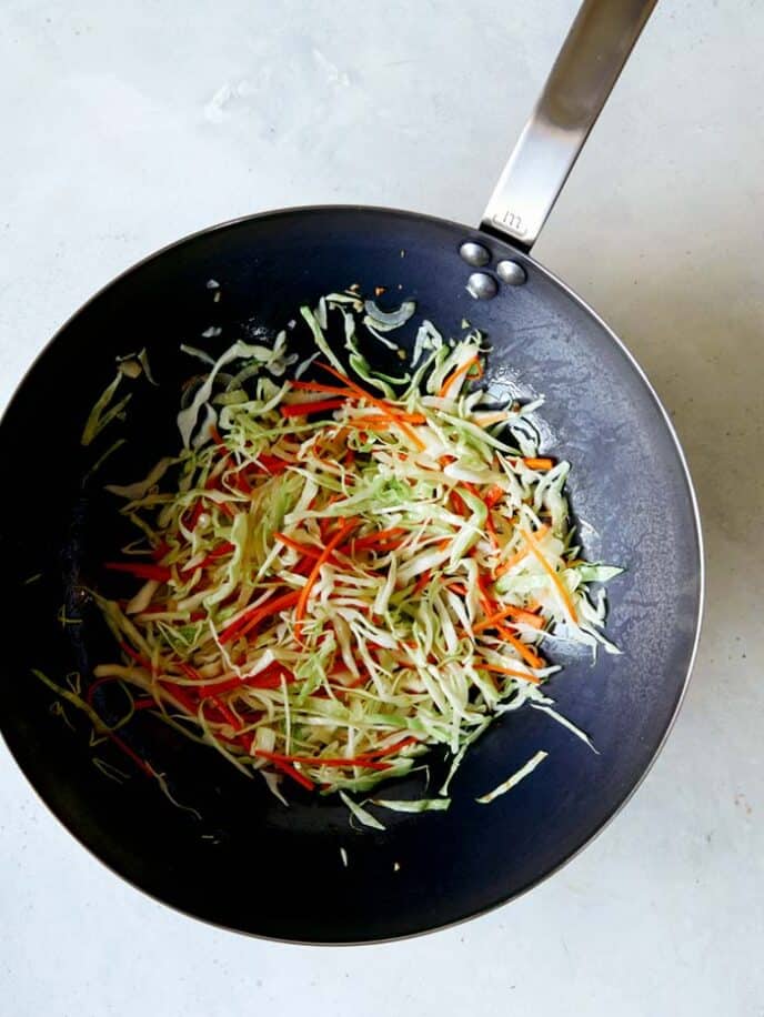 A wok with vegetables in it cooking for chow mein. 