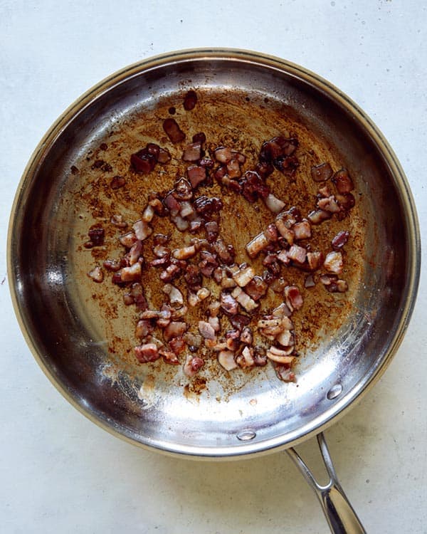 Pancetta cooking in a skillet.