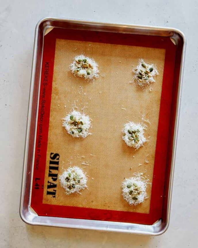 Parmesan and seeds on a baking sheet to make Parmesan Crisps.