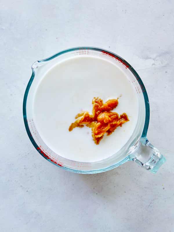 Pumpkin purée and milk combined together in a measuring cup.