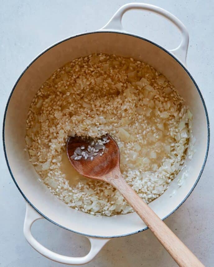 Making risotto with stock and rice in a pot.