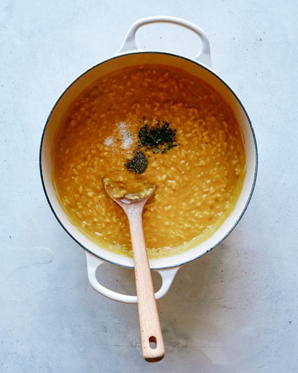 Seasoning pumpkin risotto in a stock pot.